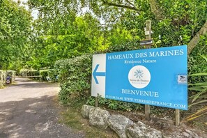 Señal para Hameaux des Marines, una residencia en plena naturaleza, con una flecha apuntando a la izquierda.