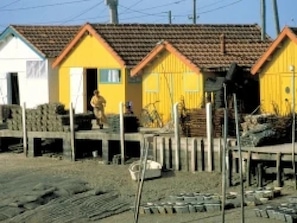 A row of single-story buildings with a simple, functional design, featuring a flat roof and a mix of white and yellow exteriors.