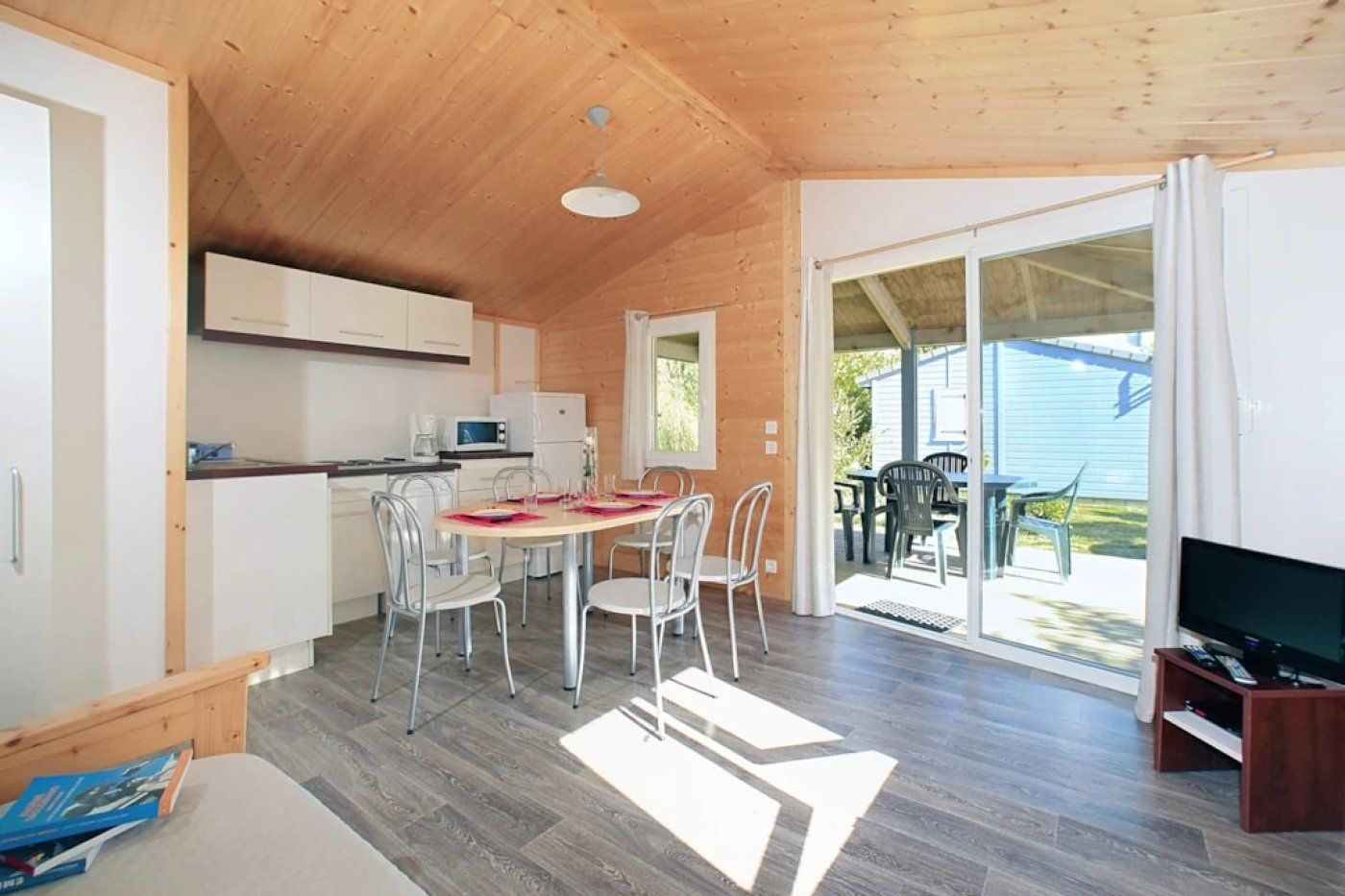 A compact kitchen with a dining area, a TV, and a sliding glass door leading to an outdoor patio.