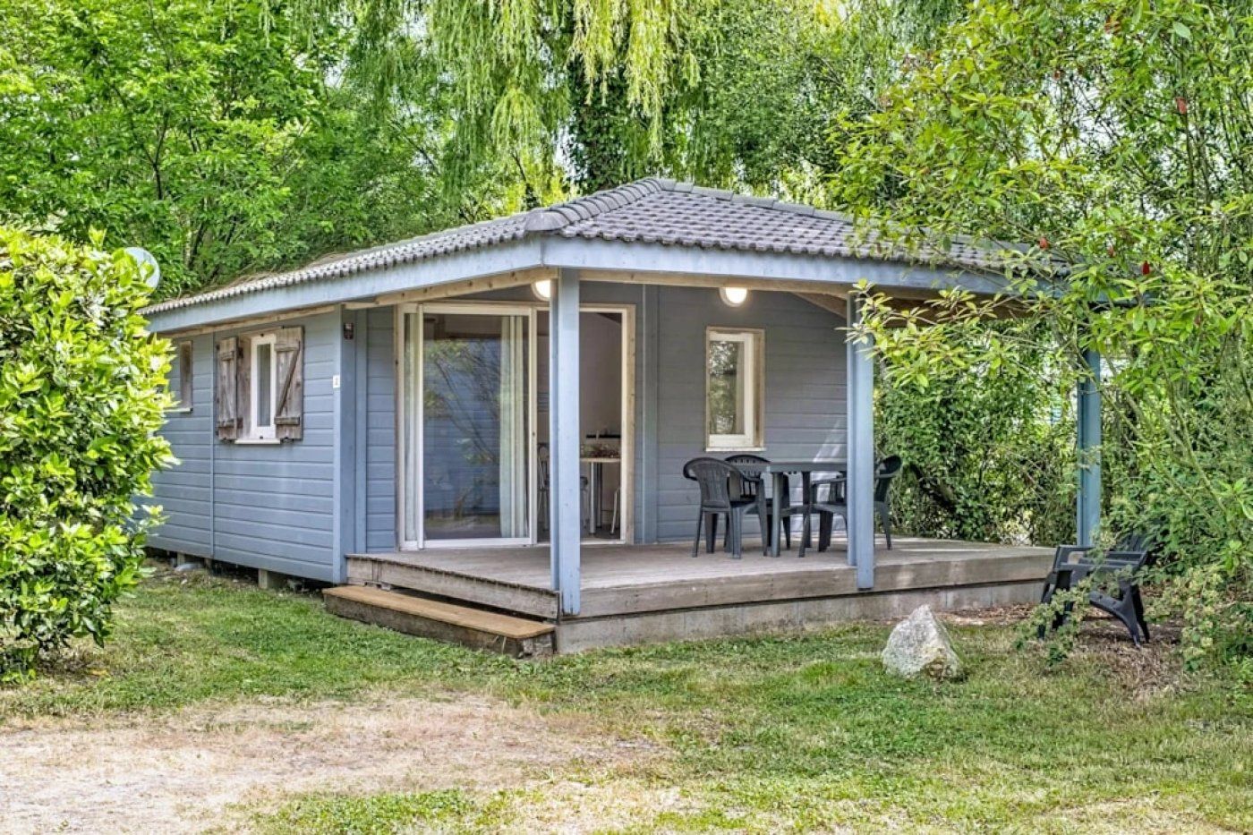 Un petit bâtiment d’un seul étage, doté d’un porche abrité et d’une table avec des chaises.