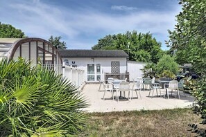 A white building with a tiled roof, surrounded by a patio with outdoor seating. - ZEcamping 2 étoiles 500m plage piscine couverte cottage TV LV clim 35m2 (Saint-Denis-d'Oléron)