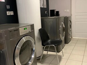 A laundry area with a washing machine, a dryer, and a chair.