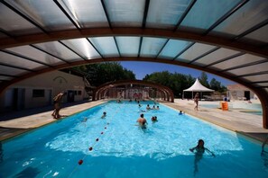 Une piscine dotée d’une zone abritée, entourée d’immeubles et d’arbres.