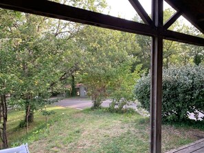 A covered outdoor area with a view of a road and trees.