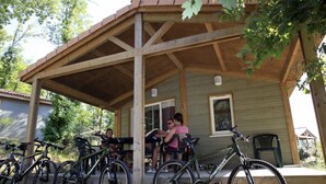 A wooden covered porch with bicycles parked in front.