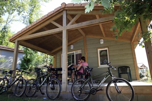 A wooden covered porch with bicycles parked in front.