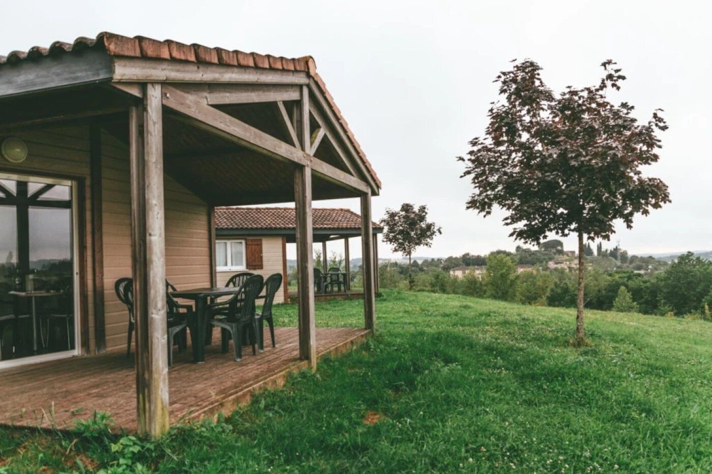 Un bâtiment en bois doté d’un patio couvert et d’un espace extérieur aménagé pour s’asseoir.