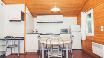 A compact kitchen with a dining area, wooden walls, and a window.