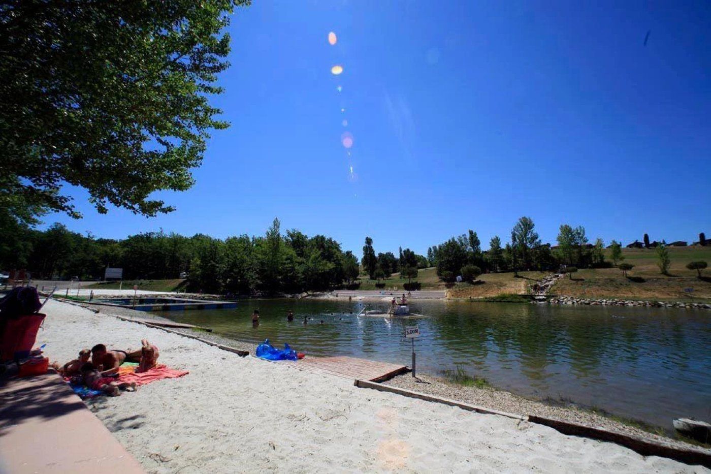 Un cadre idyllique au bord d’un lac, avec une plage de sable, une jetée et un ciel dégagé.