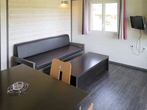 Una habitación con una mesa de madera oscura, un banco y un televisor montado en la pared.