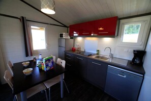 A compact kitchen with a dining table, chairs, a microwave, a sink, and cabinets.