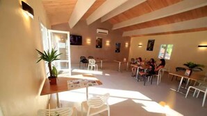 A spacious indoor area with high ceilings and natural light, featuring several tables and chairs arranged for dining or meetings.