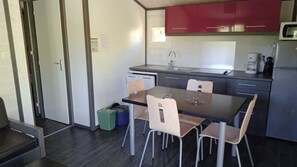 Une cuisine compacte comprenant une table et des chaises, un four à micro-ondes et une machine à café.