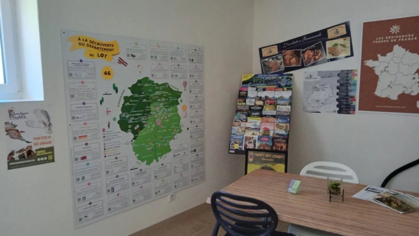Quarto com um grande mapa na parede, um mural com diversos itens e uma mesa com uma cadeira.