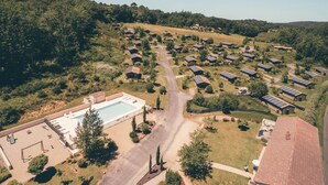 An aerial view of a residential area with multiple houses, a swimming pool, and solar panels.