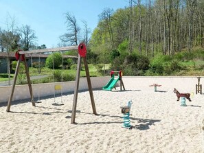 A playground with swings, a slide, and a spring rider. - ZEcamping 3 étoiles piscine chauffée dog friendly cottage TV LV clim 35m2 (Cazals)