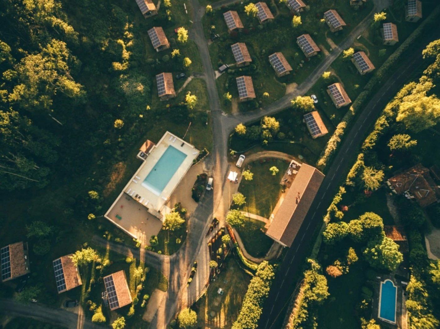 Vista aérea de una zona residencial con varias casas, una piscina y paneles solares.