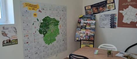 A room with a large map on the wall, a bulletin board with various items, and a table with a chair.