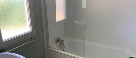 A bathroom with a bathtub, a window, and a toilet.