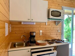 Une cuisine compacte avec des murs en bois, un four à micro-ondes, une machine à café et un évier.