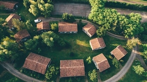 Une vue aérienne d’un ensemble de maisons traditionnelles aux toits inclinés, entourées d’une végétation luxuriante et bordées d’une route sinueuse.