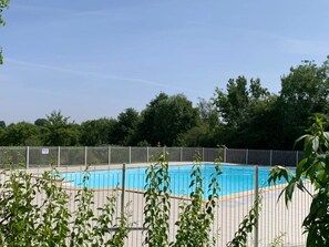 A swimming pool surrounded by a metal fence, with trees in the background. - ZEcamping 3 étoiles piscine animaux acceptés cottage TV LV BBQ 41m2 (Moutiers-sous-Chantemerle)