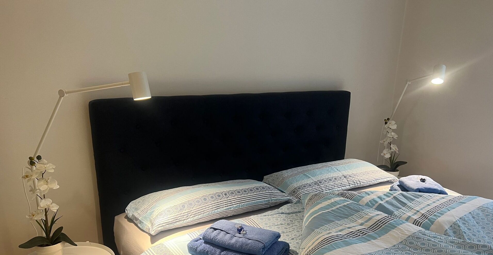 A neatly made bed with patterned bedding and two bedside lamps.