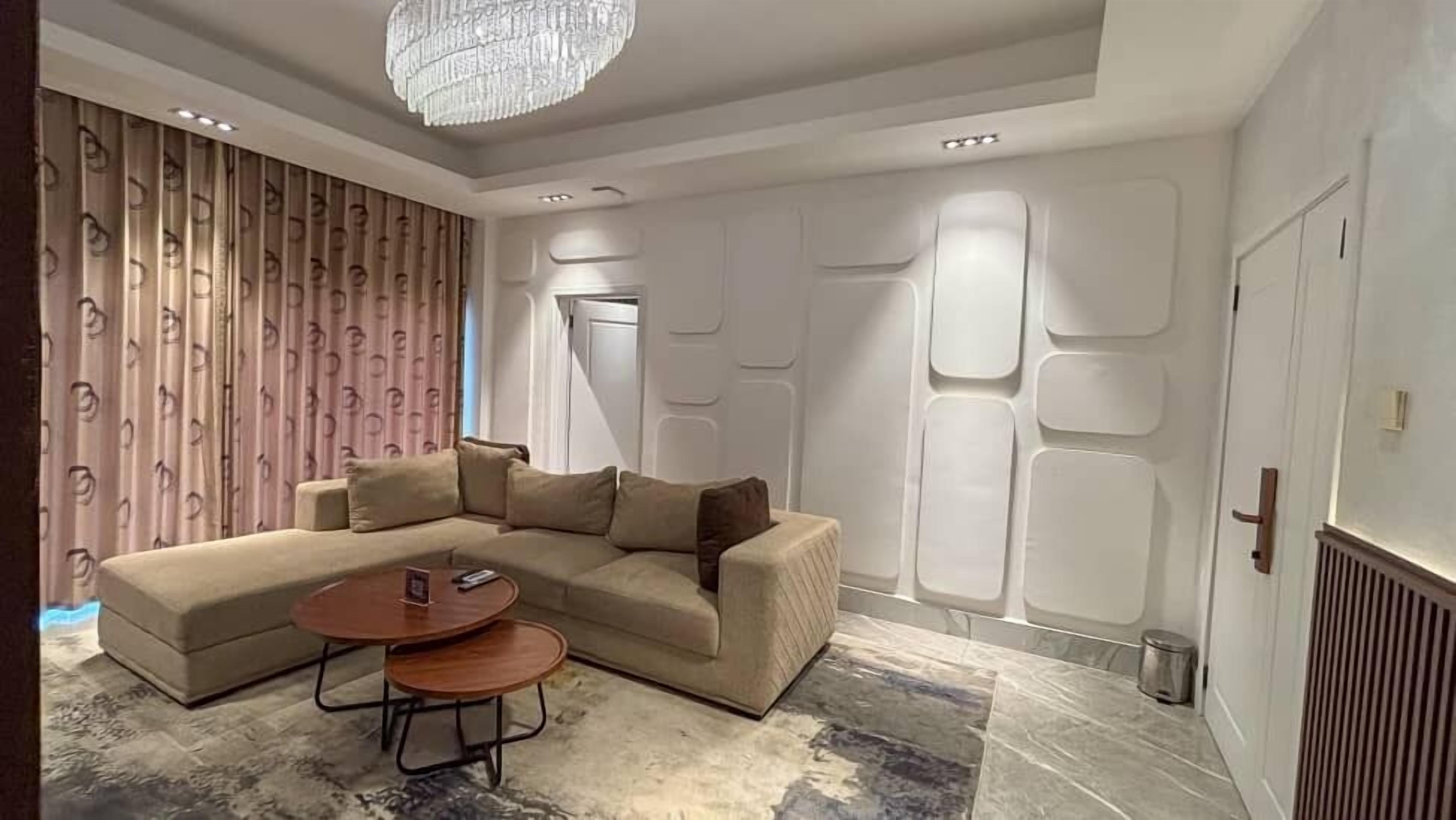 Ein modernes Wohnzimmer mit einem Ecksofa, einem runden Couchtisch und einem gemusterten Teppich.