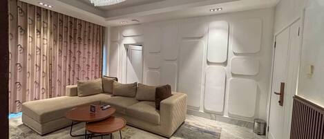 Ein modernes Wohnzimmer mit einem Ecksofa, einem runden Couchtisch und einem gemusterten Teppich.