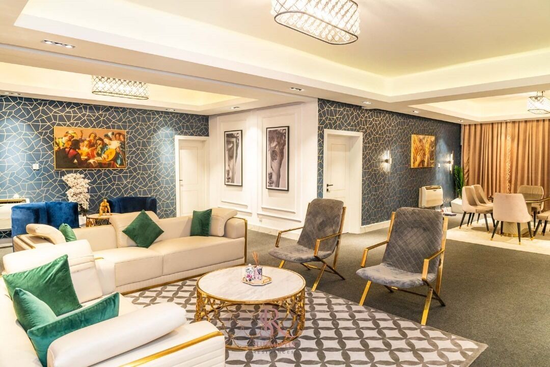 A modern hotel lobby with a white sofa, a round gold-framed coffee table, and a patterned rug.