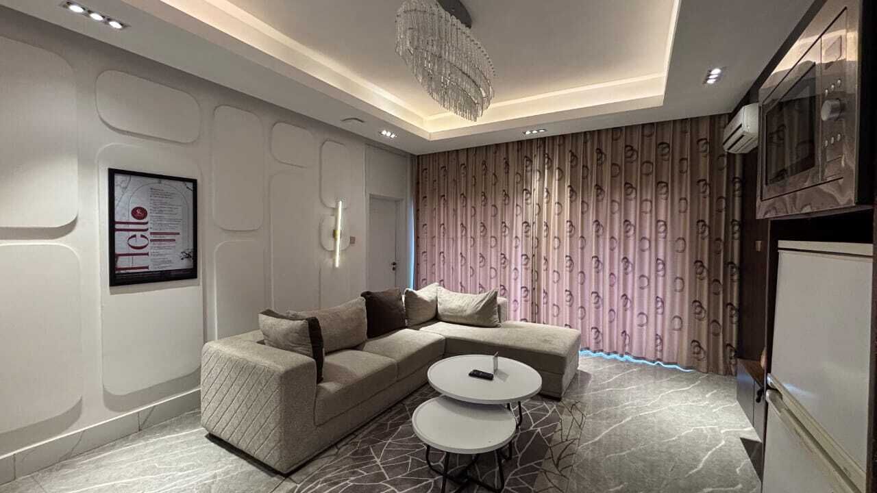 Ein modernes Wohnzimmer mit einer Eckcouch, einem kleinen runden Tisch und einer Chandelüster.