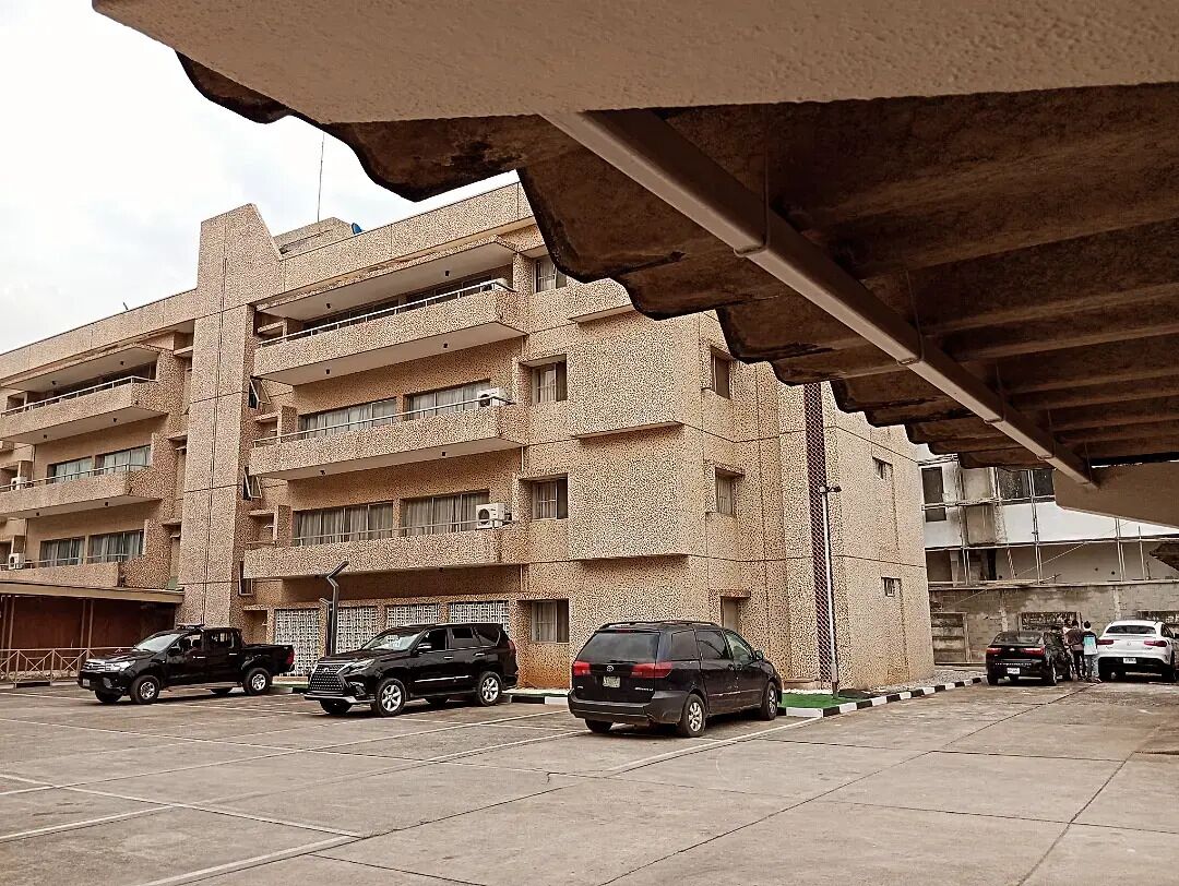 A multi-story building with several parked vehicles in front.