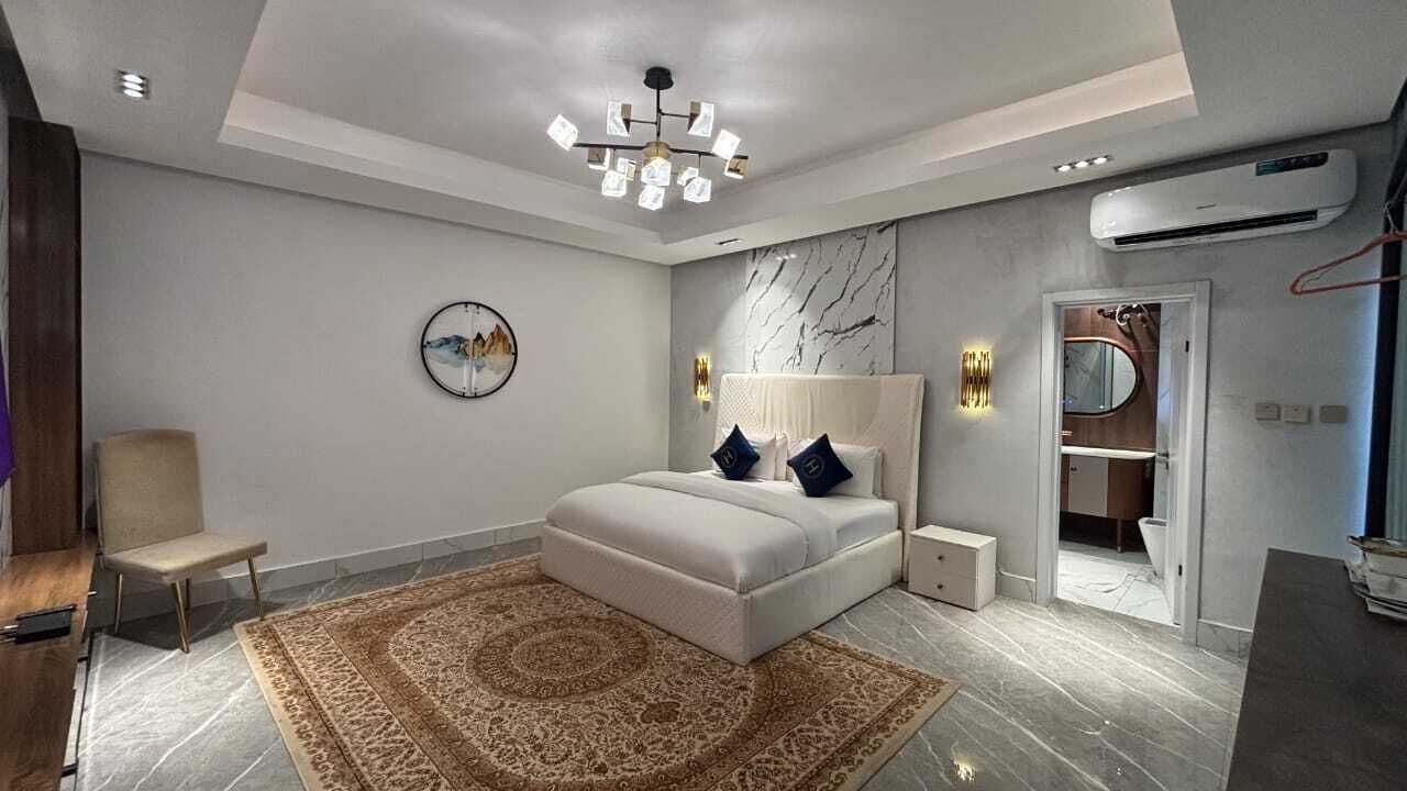 A modern bedroom with a large bed, a standing lamp, and a decorative rug.
