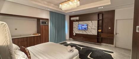 Un dormitorio moderno con una cama grande, televisión instalada en una pared de mármol y un armario empotrado.