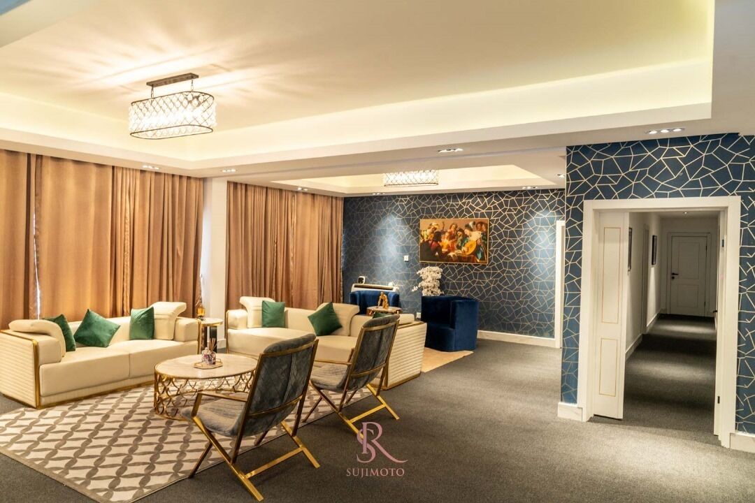 A modern living room with a sofa, chairs, a coffee table, and a decorative painting on the wall.
