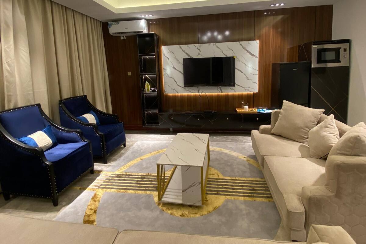 A modern living room with a chandelier, sofas, a coffee table, and a TV.
