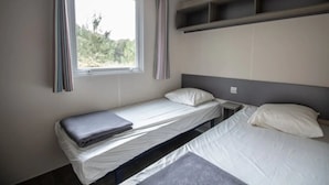 A single-bed room with a window, a bedside table, and a shelf above the bed. - ZEcamping 4 étoiles animé chiens acceptés familial piscine couverte (Saint-Michel-Escalus)