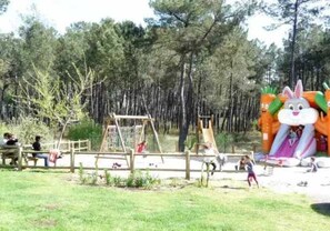 Children can play on the swing set and rabbit-themed play structure in this park setting.