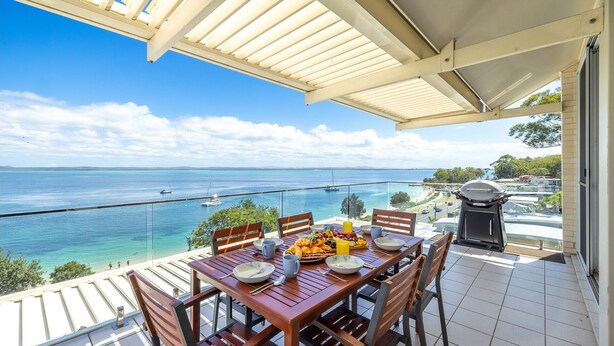 A balcony with a table set for breakfast, overlooking a clear blue sea with boats. - Classic View 2, 2 49 Victoria Pde - panoramic water views, aircon, free Wifi (Nelson Bay)