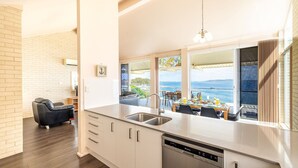 A modern kitchen with a large window overlooking a scenic view of the sea and boats. - Classic View 2, 2 49 Victoria Pde - panoramic water views, aircon, free Wifi (Nelson Bay)