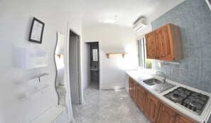 Une cuisine moderne équipée d’une cuisinière à gaz, de meubles en bois et d’une grande fenêtre qui laisse entrer la lumière naturelle.