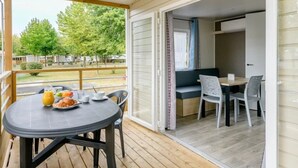 A balcony with a table set for breakfast, a sofa, and a window with curtains.