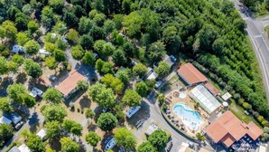 An aerial view of a residential area with multiple houses, a swimming pool, and a greenhouse.
