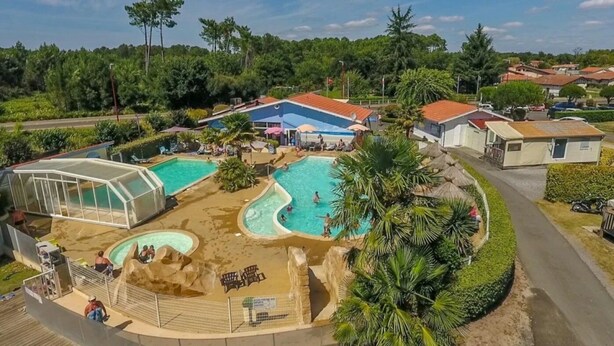 A resort with multiple swimming pools, a covered area, and a well-maintained garden.