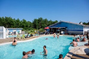 Ein Poolbereich mit mehreren Personen, Liegestühlen und einer überdachten Sitzgelegenheit.