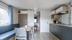 A compact kitchen with a dining area, a built-in microwave, and a seating area with a bench and chairs.