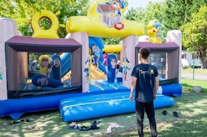 Une structure gonflable pour jeux, décorée de personnages de dessins animés, avec un toboggan et un trampoline.