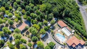 An aerial view of a residential area with multiple houses, a swimming pool, and a greenhouse.