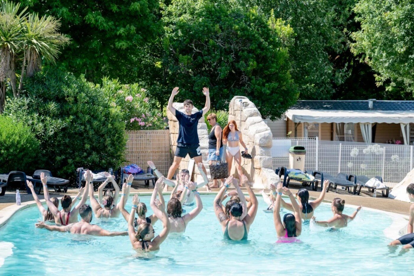 Une piscine entourée d’une végétation luxuriante, où des gens se détendent et profitent de l’eau.