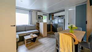 Ett kompakt bostadsutrymme med ett litet kök, en soffa, ett matbord och ett litet soffbord.